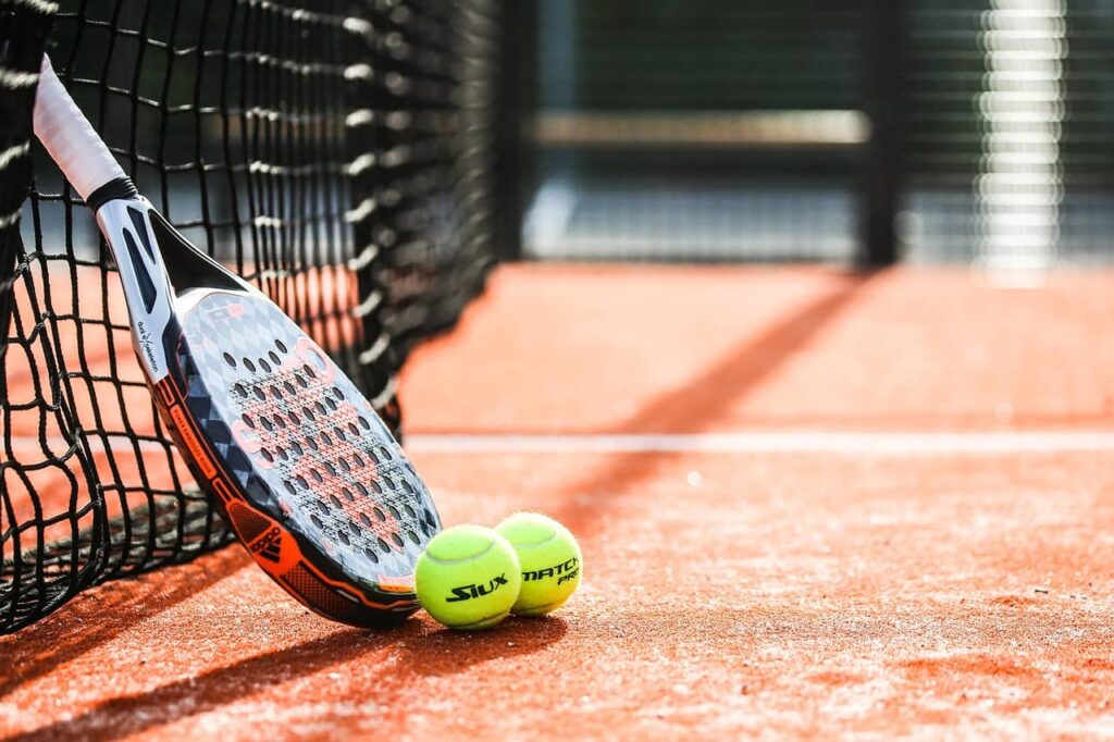 raquette et balles de padel posées au sol
